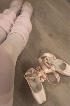 a pair of ballet shoes sitting on the floor next to a woman's legs