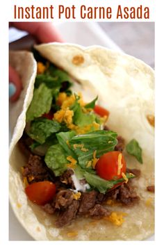 a taco filled with meat and vegetables sitting on top of a white plate next to a