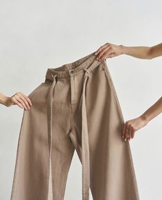 two women are holding their pants with one hand and the other is pulling them up