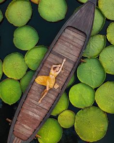 a woman in a yellow dress floating on top of a boat surrounded by water lilies