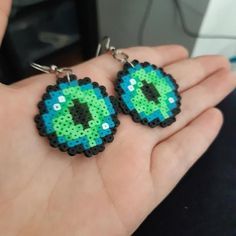 a pair of earrings made to look like an evil eye on someone's hand