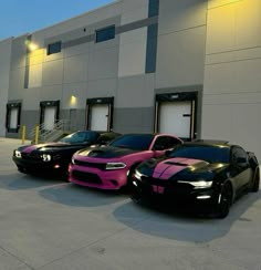 three different colored cars parked in front of a building with lights on the side of it