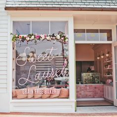 the front window of sweet lauren's bakery with pink flowers and greenery on display