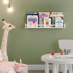 a stuffed giraffe sitting next to a white table and chair in a child's room