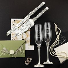 two champagne flutes are sitting next to an envelope and some other items on a table