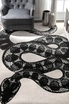 a black and white area rug with a snake on the floor next to a chair