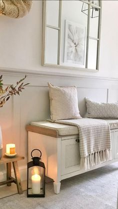 a white bench sitting next to a window filled with candles