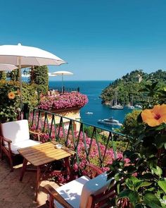 an outdoor patio with tables, chairs and umbrellas overlooking the water's edge