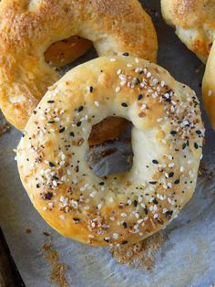 four bagels with sesame seeds and poppy seeds on them sitting on a baking sheet