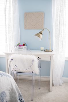 a white desk with a chair and a lamp on it in front of a window