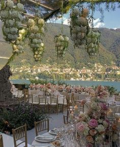 an outdoor dining area with tables and chairs set up for a formal function in front of the water