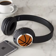 headphones and an iphone on a marble table with a cup of coffee in the background