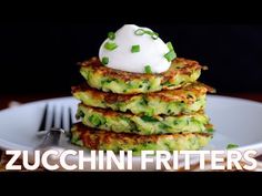 zucchini fritters stacked on top of each other with a dollop of sour cream