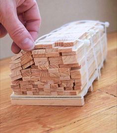 a hand reaching for a piece of wood that is stacked on top of each other