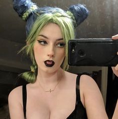 a woman taking a selfie in front of a mirror with green hair and bunny ears