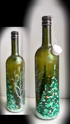 two green glass bottles with trees painted on them