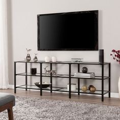 a living room with a large flat screen tv mounted on the wall above a black shelf