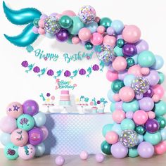 a mermaid themed birthday party with balloons and cake