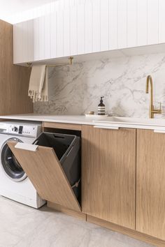 an open dishwasher in a kitchen with marble counter tops and wooden cabinets on either side