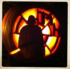 a person standing in front of a carved pumpkin