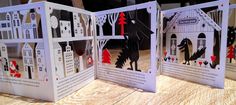 three folded cards are sitting on a table with paper cut outs in the shape of houses