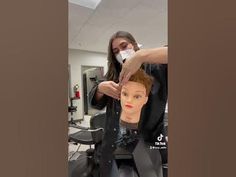 a woman cutting a mannequin's hair in a salon