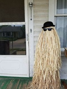 a man with long hair wearing sunglasses and a hat standing in front of a door