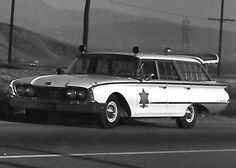 an old police car is parked on the side of the road in black and white