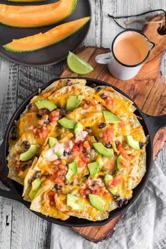 a skillet filled with chicken nachos and topped with avocado