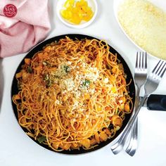 a plate of pasta with cheese and other ingredients on the side, along with utensils