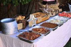 a table topped with lots of food next to a bush filled with flowers and trees