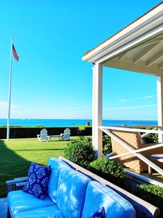 a blue couch sitting on top of a lush green field next to an american flag