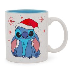 a blue and white coffee mug with an image of stitchy in a santa hat