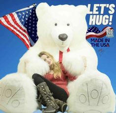 a woman sitting on top of a giant teddy bear with an american flag in the background