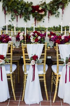 the chairs are covered with white linens and red sashes, along with burgundy flowers