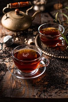 two cups of tea sit on a wooden table