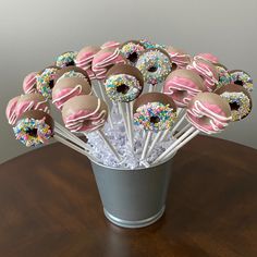 a cup full of donuts with sprinkles on them sitting on a table