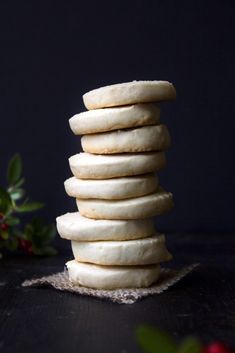 a stack of white cookies sitting on top of a wooden table next to holly leaves