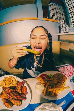 a woman sitting at a table with plates of food in front of her and an open mouth