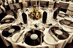 the table is set up for an event with vinyl records and sunflowers on it