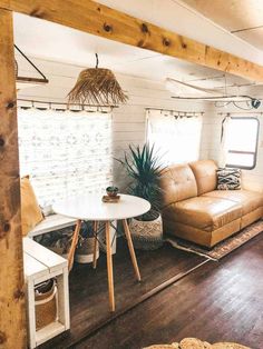 a living room filled with furniture next to a wooden floor and white brick wall behind the couch