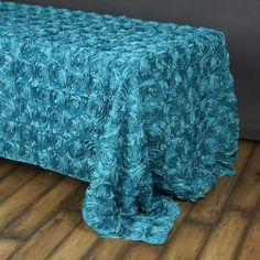 a bed covered in a blue bedspread on top of a hard wood floor