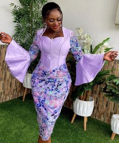 a woman in a purple and blue dress is standing on the grass with her arms outstretched