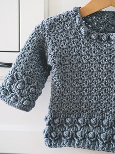 a crocheted sweater hanging on a clothes hanger