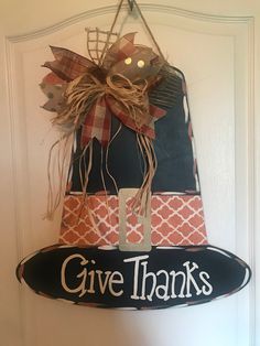 a sign that says give thanks hanging on the front door with a bow around it