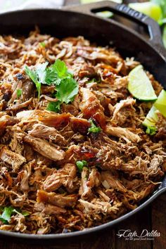 shredded pork in a skillet with limes and cilantro