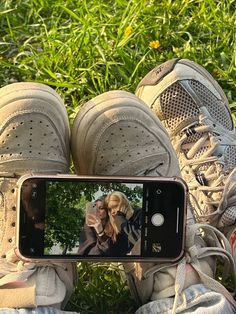 someone taking a photo with their cell phone in front of some shoes on the grass