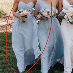 three bridesmaids in blue dresses holding bouquets and looking at the camera with an orange circle around them