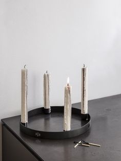 four candles are arranged on a black tray