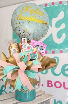 a vase filled with balloons and confetti on top of a wooden table next to a sign